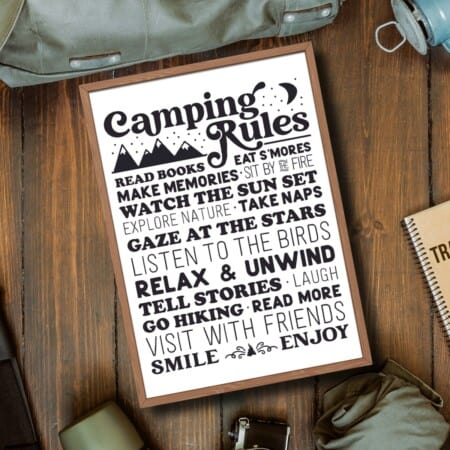 a Camping Rules poster on a wooden table with other camping items.