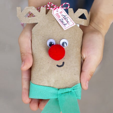 A person holding a reindeer gift bag, serving as a gift card holder.